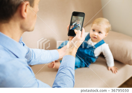 Attentive father taking a photo of his cute baby 36795030