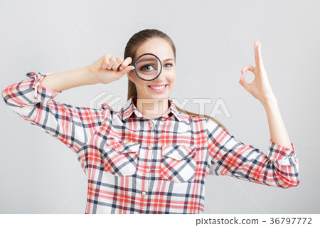 woman looks through a magnifying glass 36797772