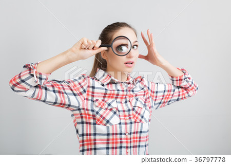 woman looks through a magnifying glass 36797778