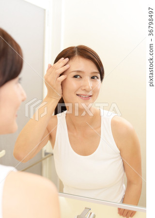 A woman looking at a mirror and smiling 36798497
