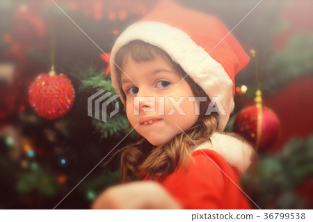 Little girl in Santa's dress by the Christmas tree Little girl in Santa's dress by the Christmas tree 36799538