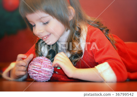 Little girl in Santa's dress playing with a ball Little girl in Santa's dress playing with a ball 36799542
