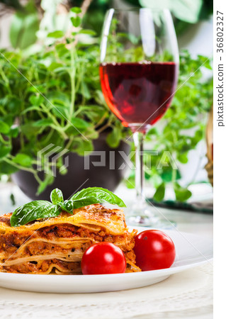 Piece of tasty hot lasagna with red wine.. Piece of tasty hot lasagna with red wine.. 36802327