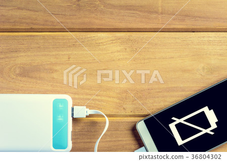 top view charge the smartphone on a wooden table. top view charge the smartphone on a wooden table. 36804302