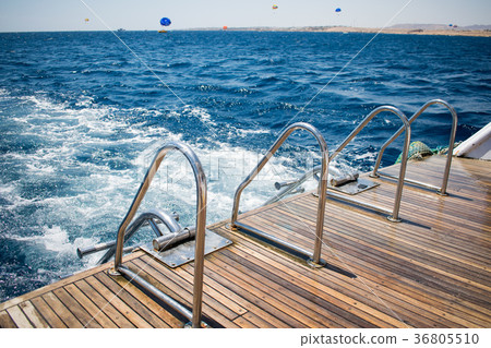 yacht's stern with two boarding ladders.azure sea yacht's stern with two boarding ladders.azure sea 36805510