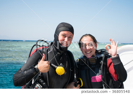 two smiling divers in wet suits show ok.azure sea two smiling divers in wet suits show ok.azure sea 36805548