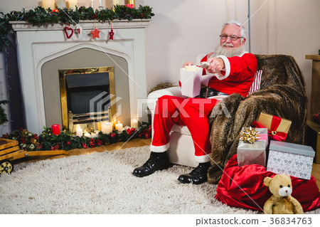 Santa Claus holding television remote control 36834763