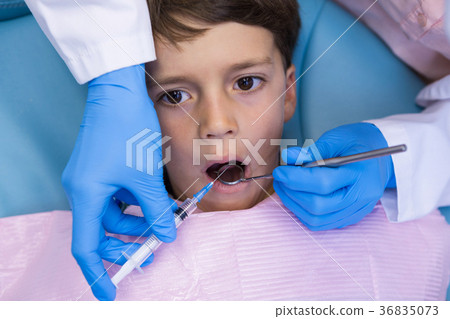 Dentist holding medical equipment while examining boy Dentist holding medical equipment while examining boy 36835073