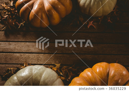 Autumn leaves by pumpkins on wooden table 36835229