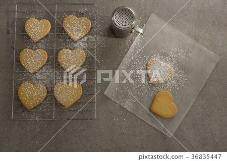 Raw heart shape cookies on baking tray with flour shaker strainer and wax paper Raw heart shape cookies on baking tray with flour shaker strainer and wax paper 36835447