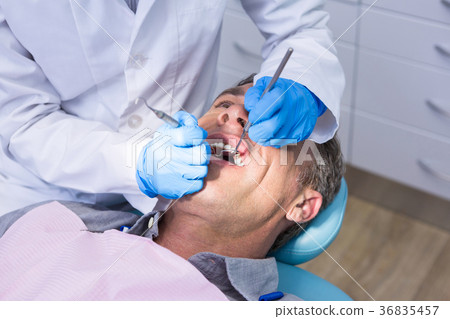 Dentist giving dental treatment to man at medical clinic Dentist giving dental treatment to man at medical clinic 36835457