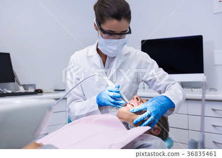Dentist holding equipment while giving treatment to man Dentist holding equipment while giving treatment to man 36835461
