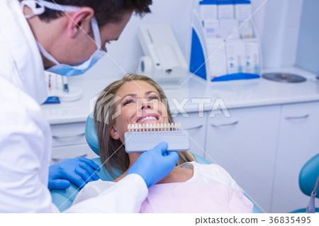 Doctor holding tooth whitening equipment by smiling patient 36835495
