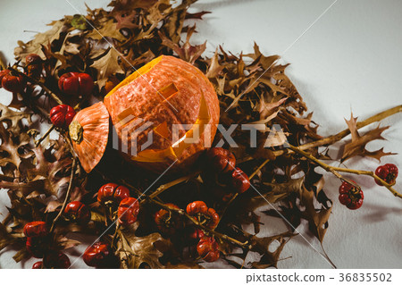 High angle view of jack o lantern with small pumpkins and autumn leaves 36835502