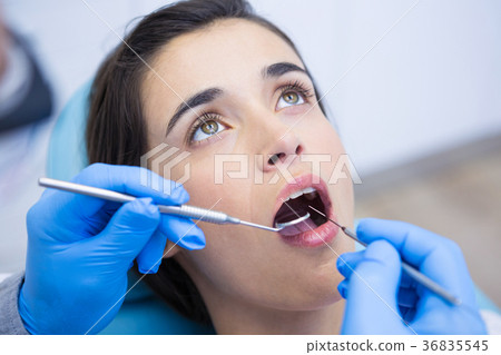 Dentist holding equipments while examining woman at medical clinic 36835545