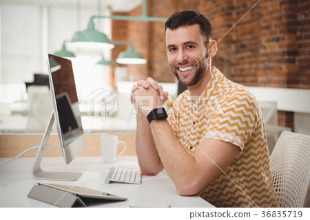 Portrait of smiling male executive sitting at desk Portrait of smiling male executive sitting at desk 36835719