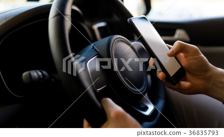 Close-up of man using smartphone while test driving in car Close-up of man using smartphone while test driving in car 36835793
