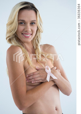 Portrait of smiling woman covering breast with pink ribbon on hand Portrait of smiling woman covering breast with pink ribbon on hand 36836364
