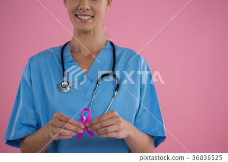 Mid section of happy female doctor in scrubs showing Breast Cancer Awareness ribbon Mid section of happy female doctor in scrubs showing Breast Cancer Awareness ribbon 36836525