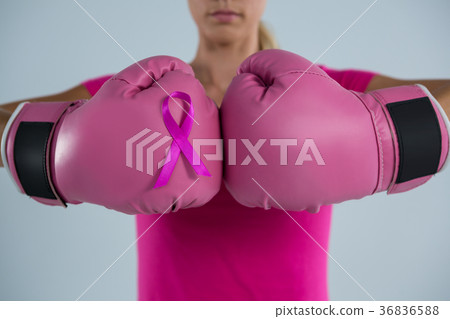 Mid section of woman with boxing gloves and pink ribbon Mid section of woman with boxing gloves and pink ribbon 36836588