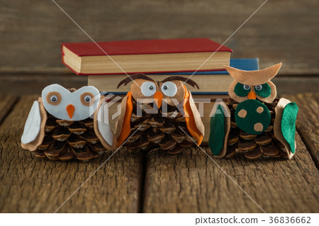 Owl decorated with pine cone and book stack on wooden table Owl decorated with pine cone and book stack on wooden table 36836662