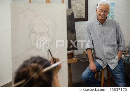 Senior man watching while artist drawing on canvas Senior man watching while artist drawing on canvas 36837170