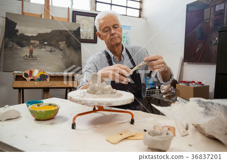 Attentive senior man molding clay Attentive senior man molding clay 36837201