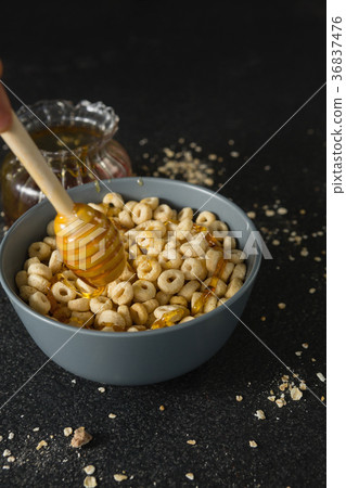 Honey being poured in bowl of cereal rings 36837476
