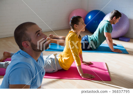 Yoga instructor with students practicing cobra pose in club 36837795