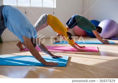 Instructor with students practicing downward facing dog pose in health club 36837829
