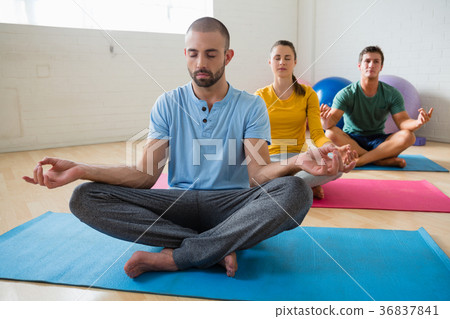 Yoga instructor with students meditating at club  36837841