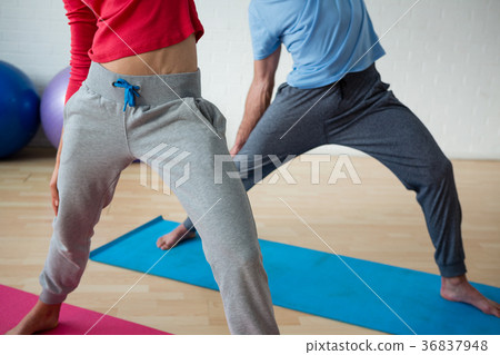 Low section of male instructor exercising with female student in club 36837948