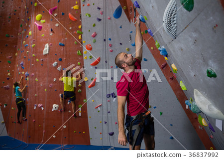 Dedicated athletes and trainer climbing wall in club 36837992