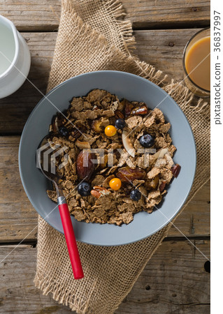 Bowl of wheat flakes, blueberry and golden berry with milk jug 36837997