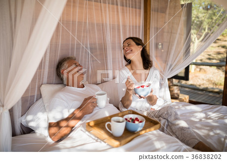Happy couple having breakfast in canopy bed Happy couple having breakfast in canopy bed 36838202