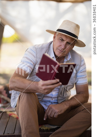 Attentive man reading book in cottage Attentive man reading book in cottage 36838401
