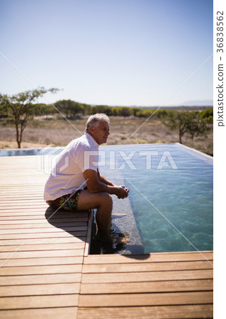Thoughtful man sitting near pool side Thoughtful man sitting near pool side 36838562