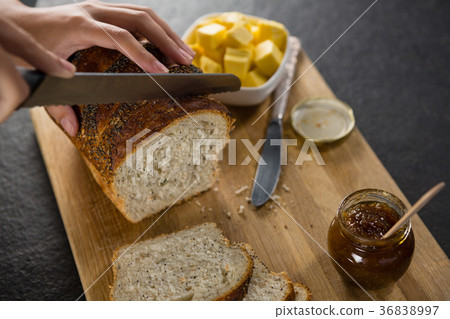 Woman cutting freshly baked multigrain bread 36838997