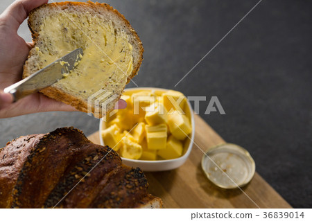 Woman applying butter over multigrain bread slice 36839014