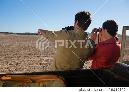 Rear view of couple looking through binoculars at landscape Rear view of couple looking through binoculars at landscape 36839122
