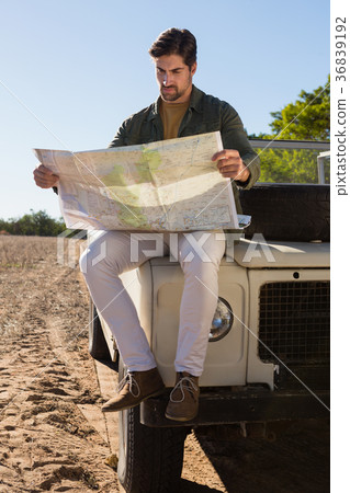 Full length of man reading map while sitting on off road vehicle 36839192