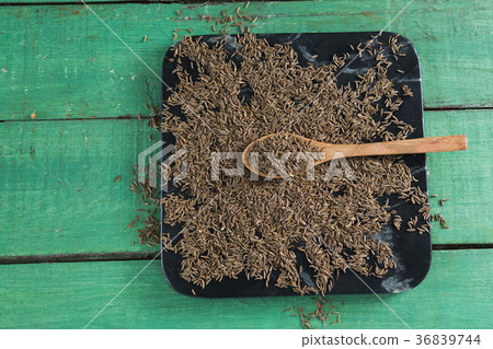 Cumin with spoon in tray on wooden table 36839744