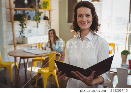 Portrait of confident waitress with menu in cafe 36839745