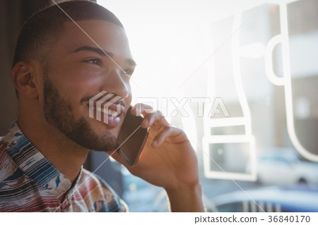 Young man talking on phone in cafe Young man talking on phone in cafe 36840170