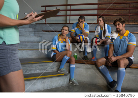 Mid section of coach standing by volleyball players 36840790