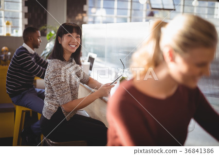 Smiling young woman sitting in cafeteria 36841386