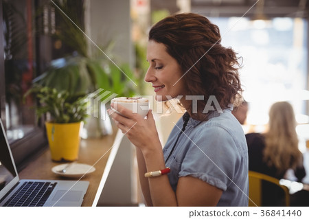 Young woman smelling coffee while sitting at cafe 36841440