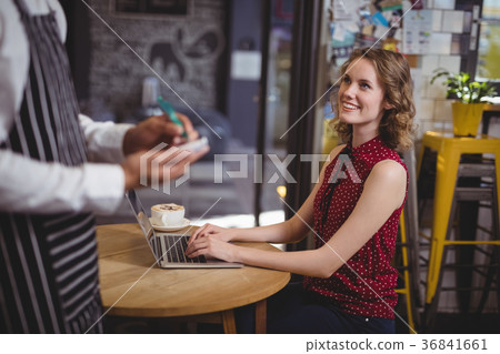 Midsection of waiter holding notepad while standing by smiling young female customer 36841661