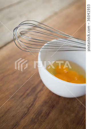 High angle view of egg in bowl with wire whisk High angle view of egg in bowl with wire whisk 36841933