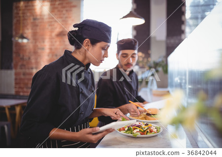 Young wait staff discussing over food with digital tablet and clipboard at counter Young wait staff discussing over food with digital tablet and clipboard at counter 36842044